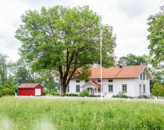 Hvitmalt trebygning med hage foran