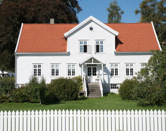 Hvitmalt trebygning med hage foran