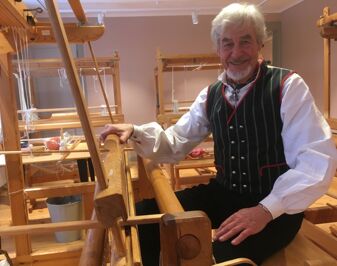 Peter Paaske iført vest, sittende ved en gammel vev